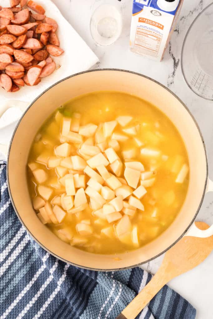 Cubed potatoes added into the simmering broth in the soup pot, ready to cook until tender.