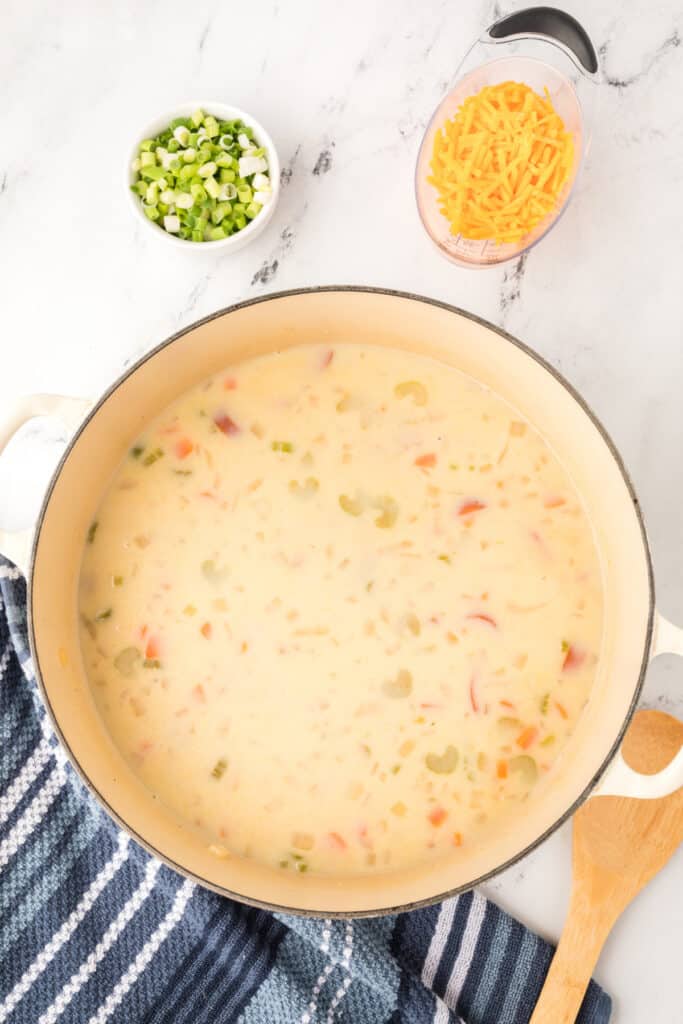 Pot of simmering cheesy kielbasa potato soup with a smooth, creamy broth.