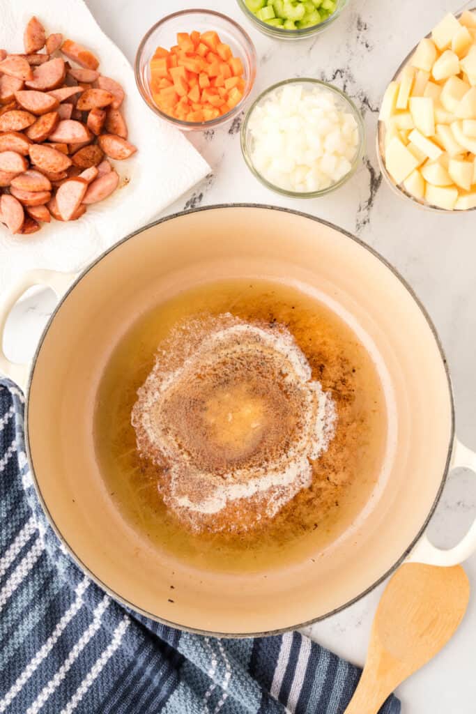 Cooked sausage set aside on a paper towel while butter melts in the same pot to start the soup base.