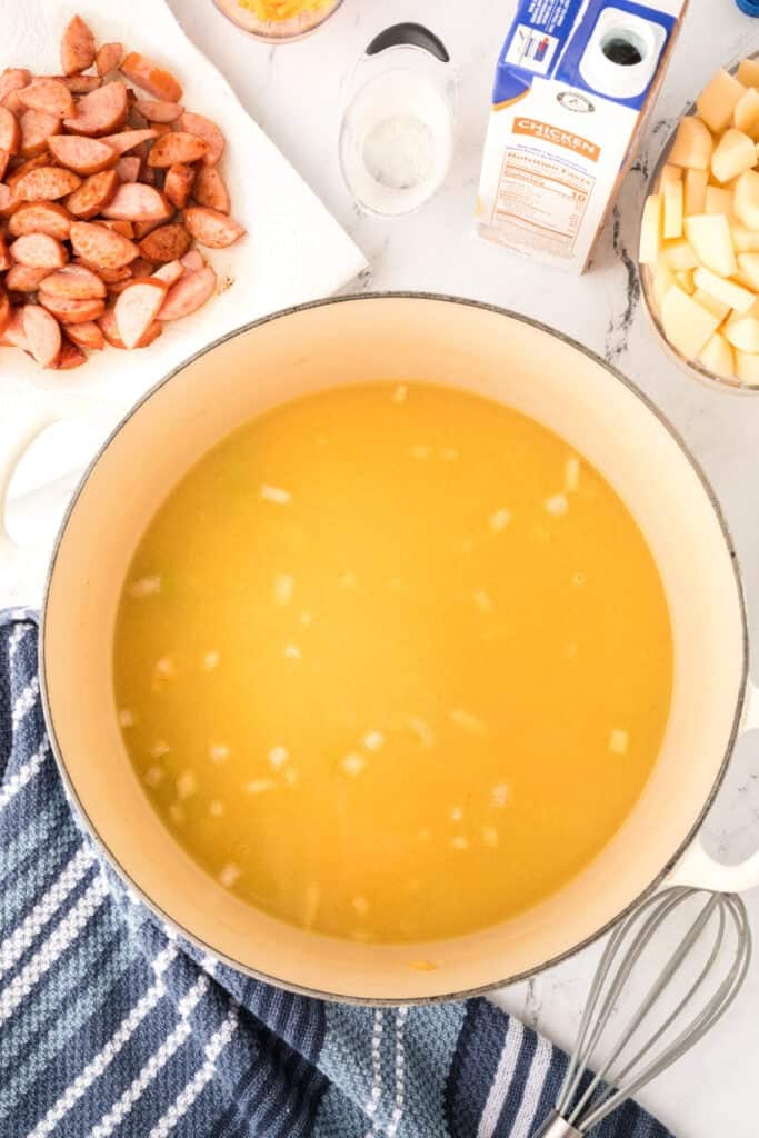 Chicken broth poured into the pot with the vegetable mixture, creating the soup base.