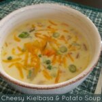 Cheesy Kielbasa & Potato Soup in bowl with spoon.