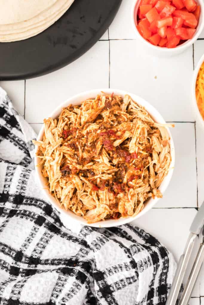 Shredded chipotle lime chicken tossed with sauce in a serving bowl