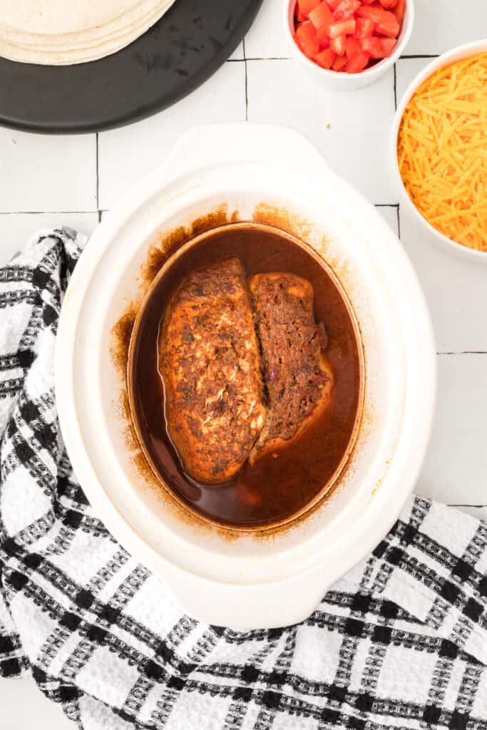 Cooked chipotle lime chicken breasts in a slow cooker with cooking juices