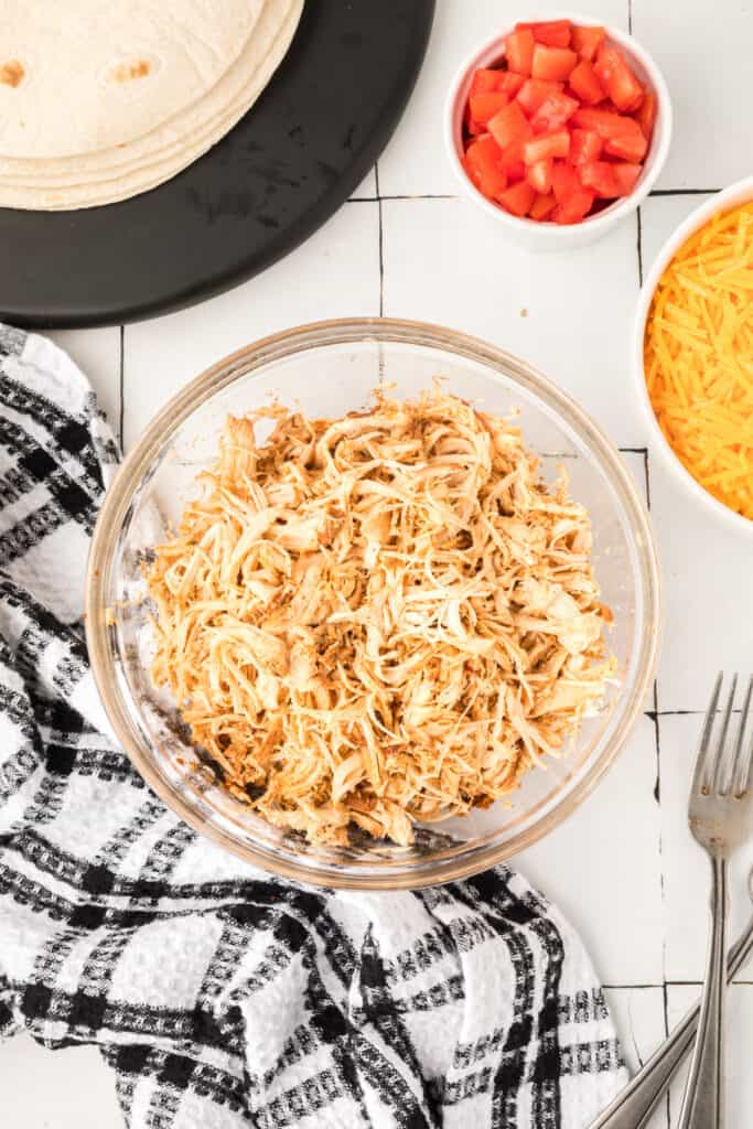 Shredded chipotle lime chicken in a glass bowl before adding sauce