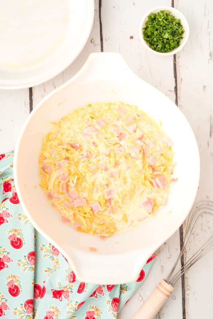 Mixing bowl filled with the combined ham, cheese, vegetables, and egg mixture before baking.