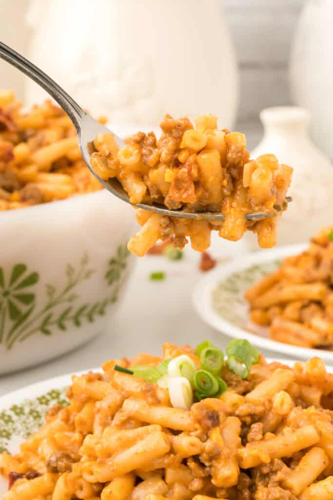 fork lifting a bite of BBQ Beefy Mac and Cheese showing ground beef and creamy sauce