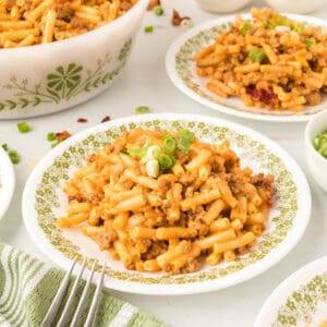 BBQ Beefy Mac and Cheese on a plate with bacon and green onions styled for a square image