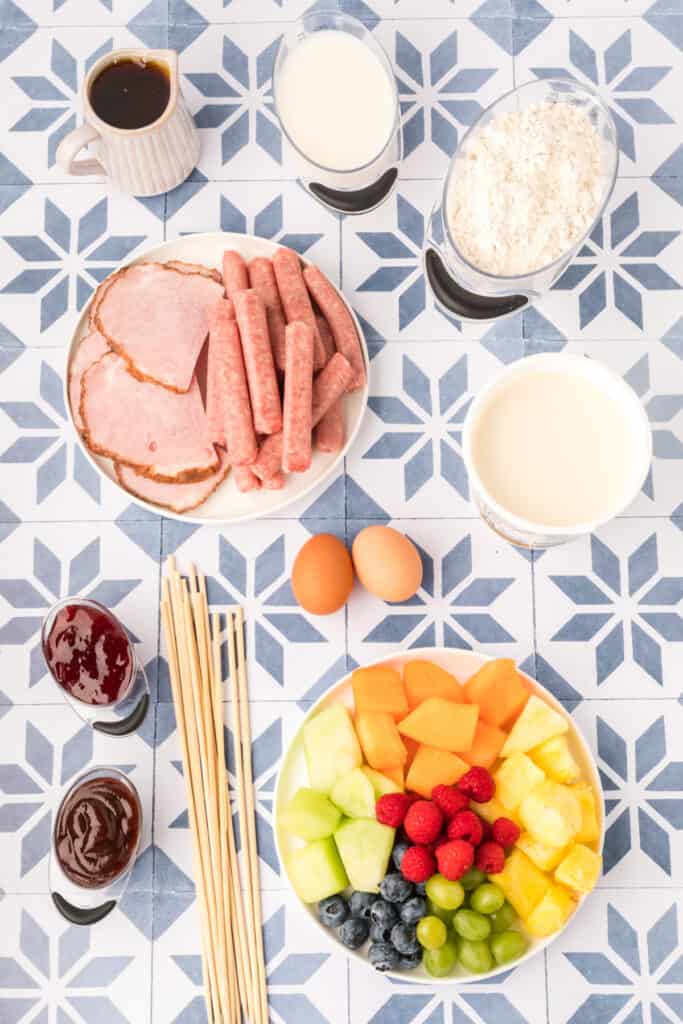 Ingredients for Breakfast Kabobs and Mini Pancakes with fruit, sausage, ham, pancake mix, eggs, yogurt, and dipping sauces