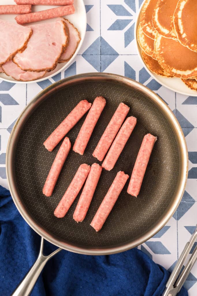 Breakfast sausage links cooking in skillet for Breakfast Kabobs and Mini Pancakes