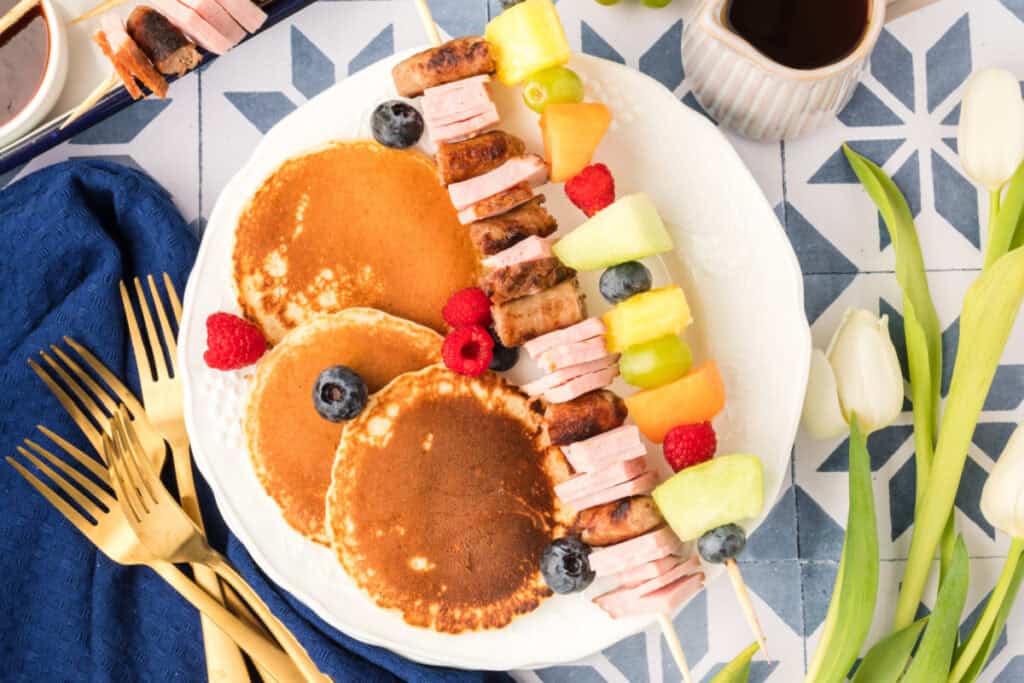 Breakfast Kabobs and Mini Pancakes served on plate with fruit and savory breakfast skewers