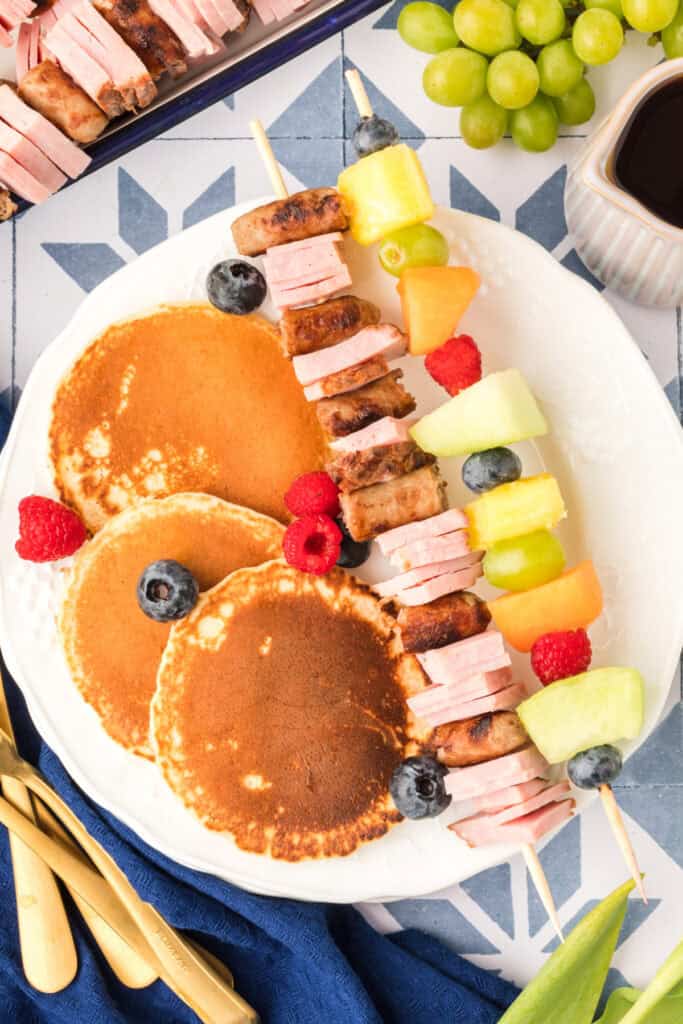 Breakfast Kabobs and Mini Pancakes served on plate with fruit and savory breakfast skewers