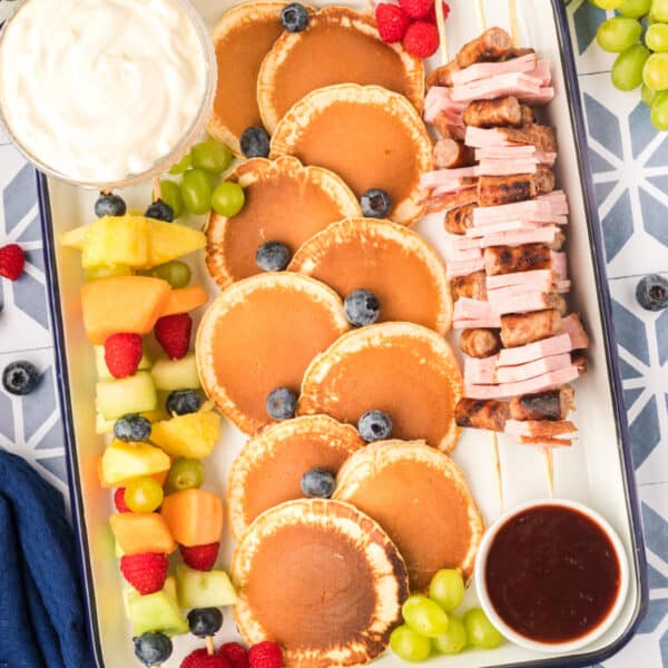Square image of Breakfast Kabobs and Mini Pancakes with fruit kabobs, mini pancakes, yogurt dip, and savory breakfast skewers