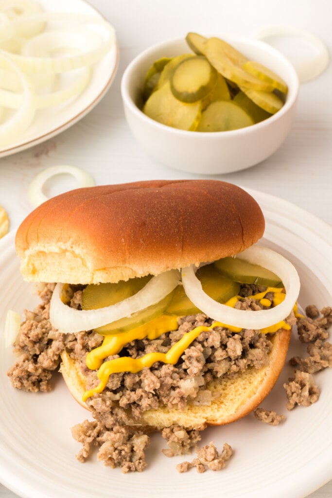Maid-Rite Sandwich with onions, pickles, and mustard on plate