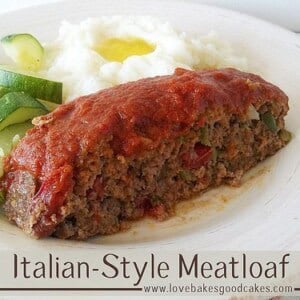 italian style meatloaf on white plate with cooked zucchini and mashed potatoes with butter