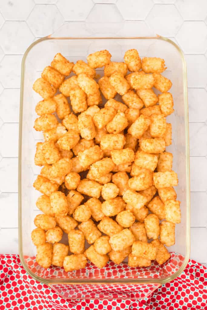 Partially baked tater tots in a glass baking dish.