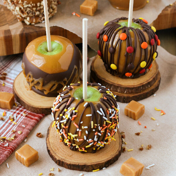 finished and decorated caramel apples on wooden coasters