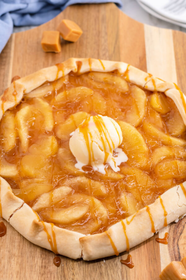 finished caramel apple galette with a scoop of ice cream on a wooden cutting board