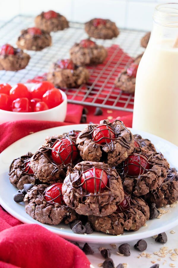 thumbprints cookies on plate with glass milk bottle and bowl of cherries