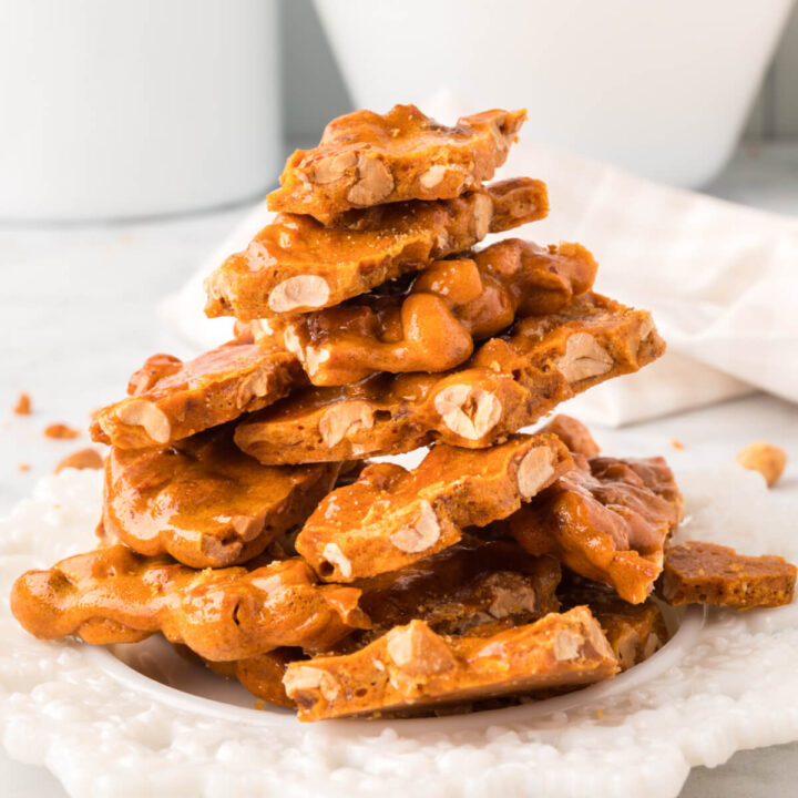 microwave peanut brittle stacked on a white plate