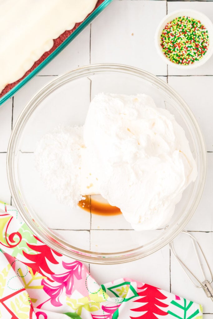 Cream cheese, whipped topping, powdered sugar, and vanilla in a glass bowl before mixing.
