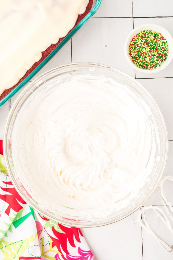 Cream cheese topping mixture fully blended and smooth in a glass mixing bowl.