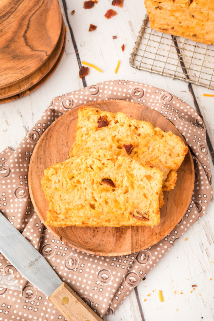 two slices of bacon cheddar beer bread on wooden plate