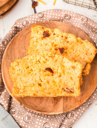 two slices of bacon cheddar beer bread on wooden plate