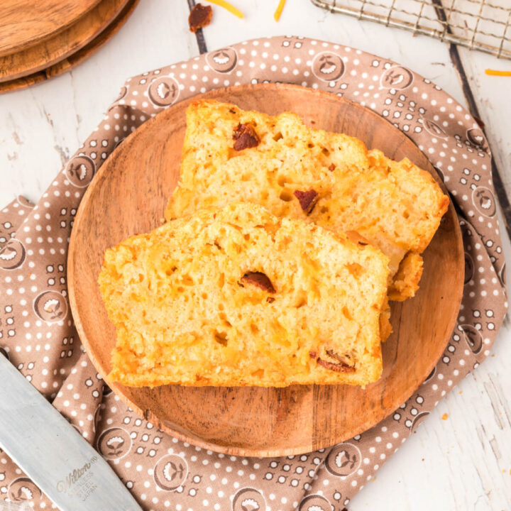 two slices of bacon cheddar beer bread on wooden plate