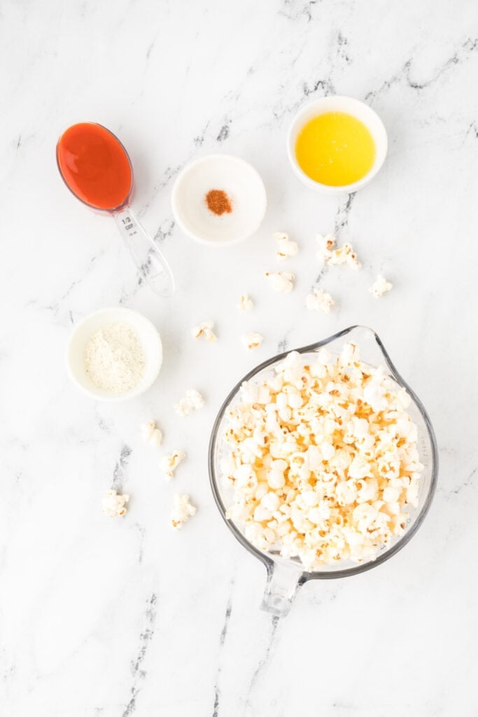 Ingredients for Buffalo Ranch Popcorn including popcorn, buffalo sauce, melted butter, cayenne pepper, and ranch seasoning