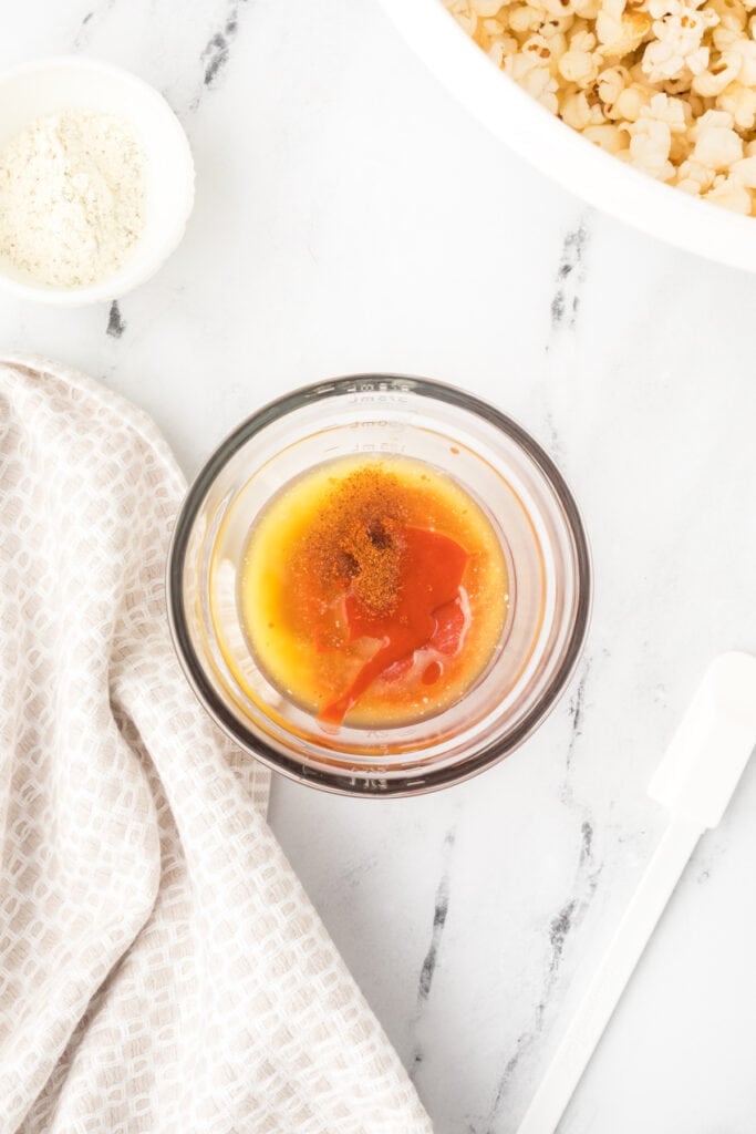 Buffalo sauce, melted butter, and cayenne pepper in a bowl for Buffalo Ranch Popcorn
