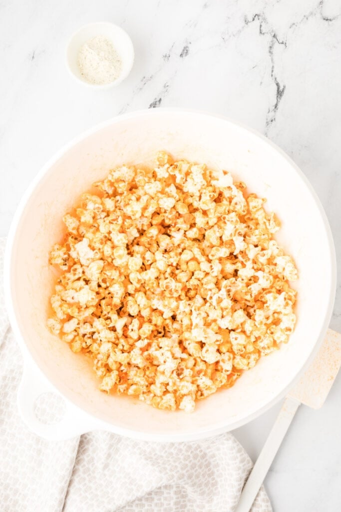Buffalo Ranch Popcorn tossed with buffalo sauce and ranch seasoning in a mixing bowl