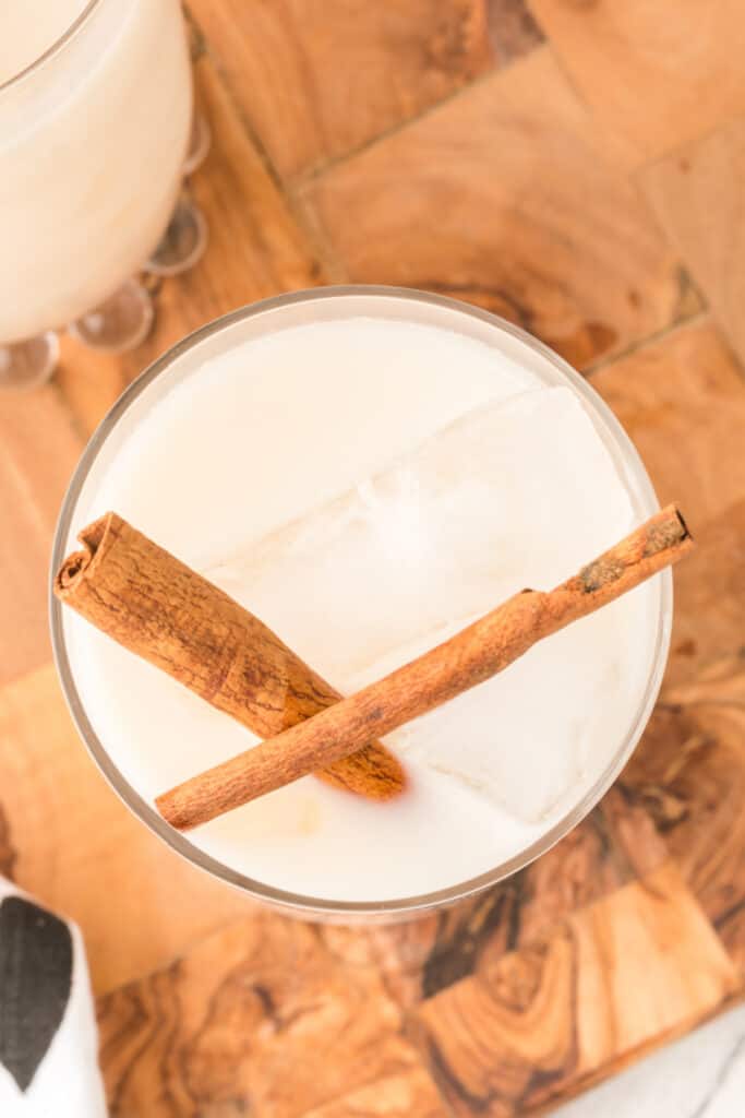 looking down on a glass filled with ice and horchata and garnished with cinnamon sticks