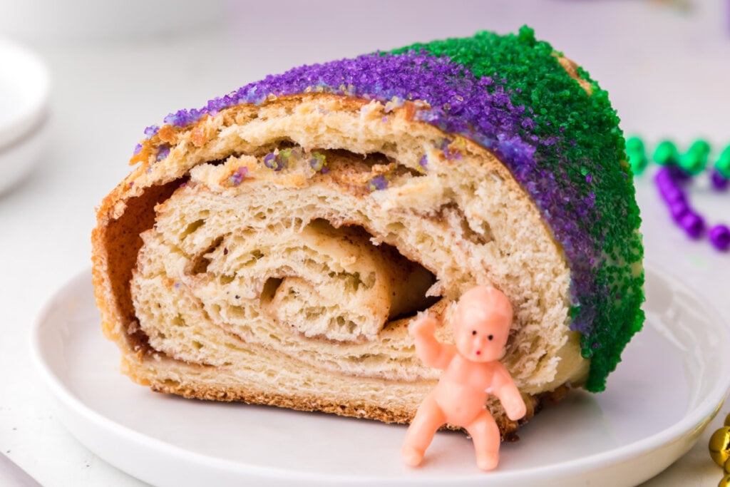 slice of new orleans king cake with plastic baby