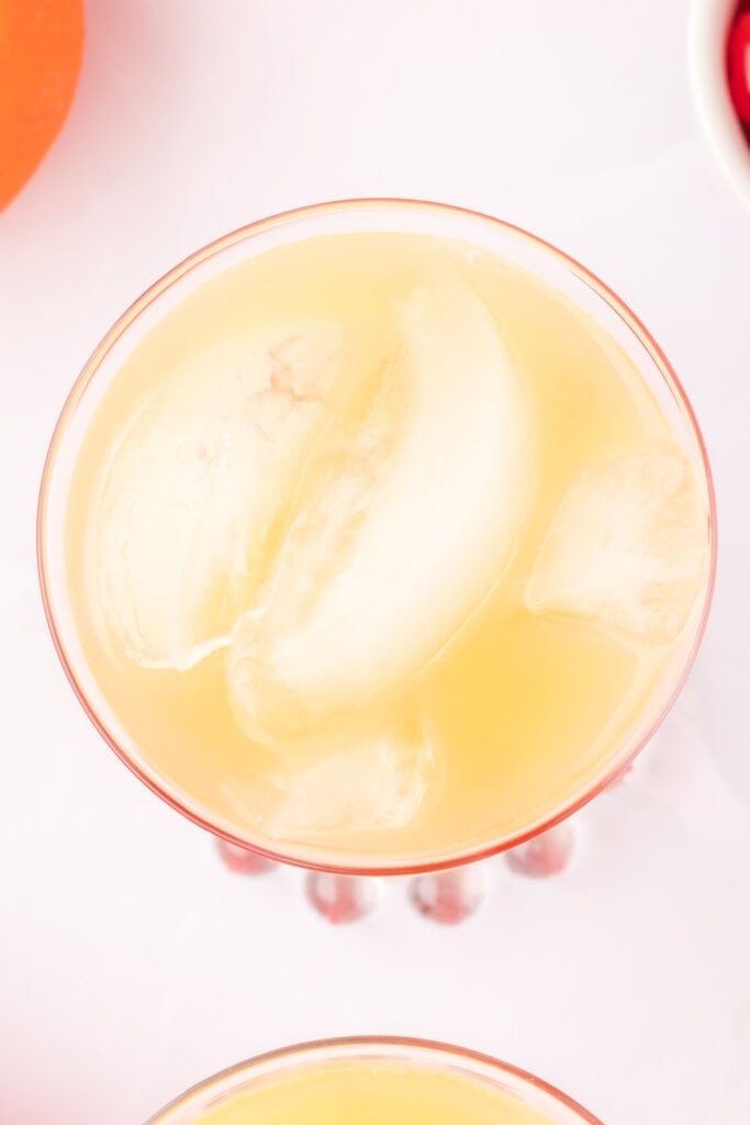 glass filled with orange juice and ice viewed from above
