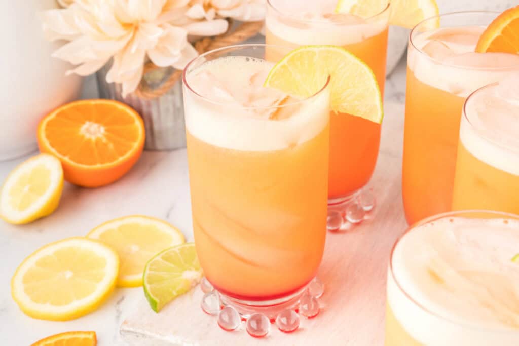 Multiple glasses of homemade Cactus Cooler mocktail with citrus garnishes and layered grenadine at the bottom