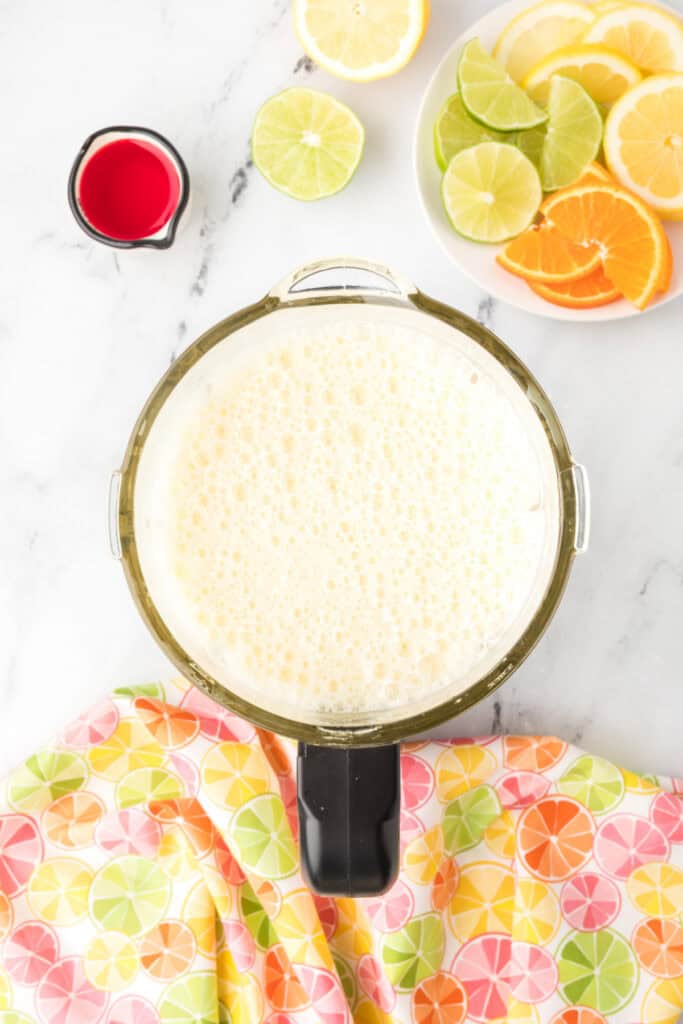 Frothy blended citrus mixture in a blender pitcher for homemade Cactus Cooler mocktail recipe