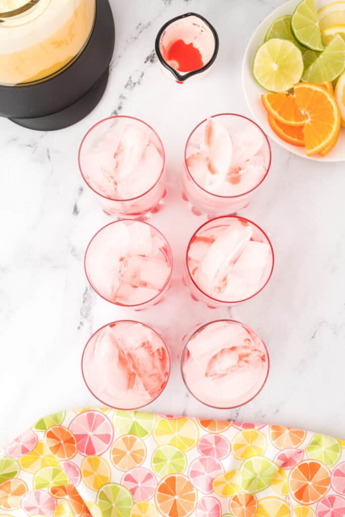 Ice-filled glasses drizzled with grenadine for layering homemade Cactus Cooler mocktails
