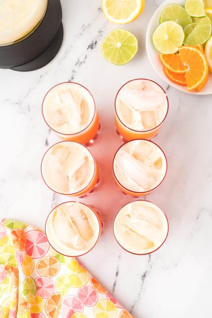 Glasses filled with homemade Cactus Cooler recipe showing orange-pineapple drink layered over grenadine and ice