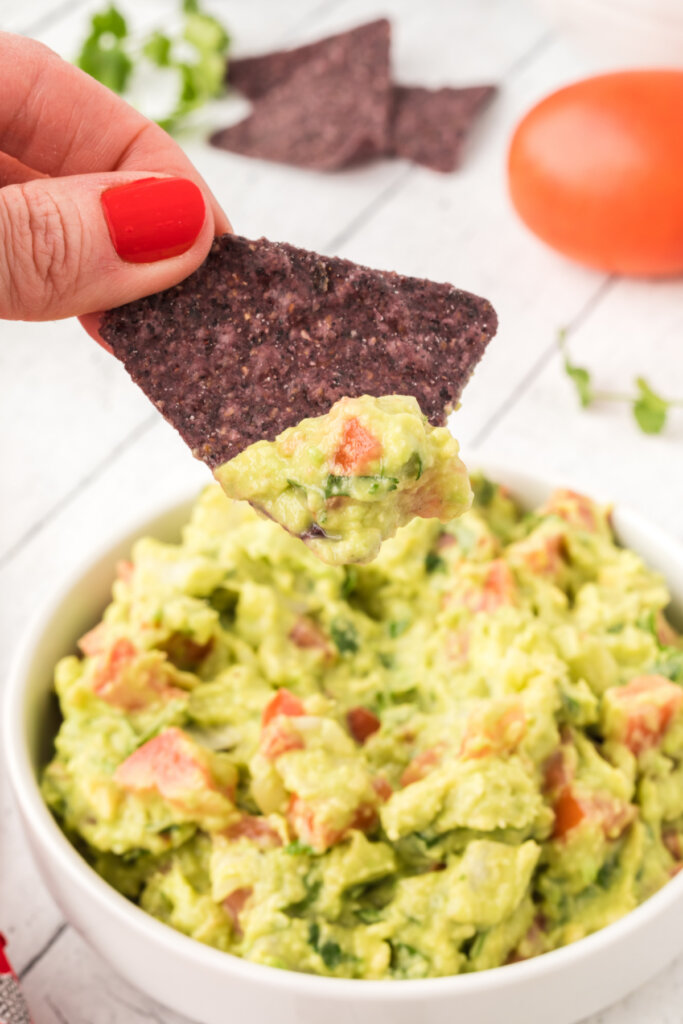 tortilla chip scooping guacamole