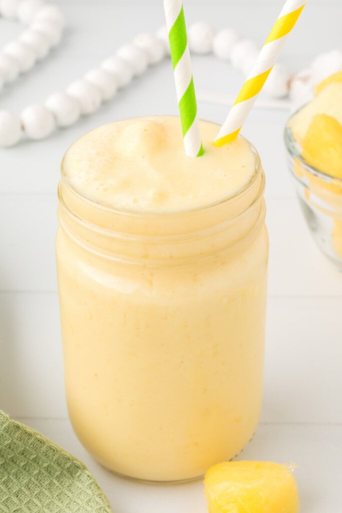 pineapple orange smoothie in mason jar with two straws