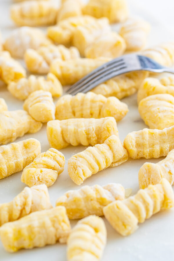 homemade potato gnocchi rolled out and on a white surface