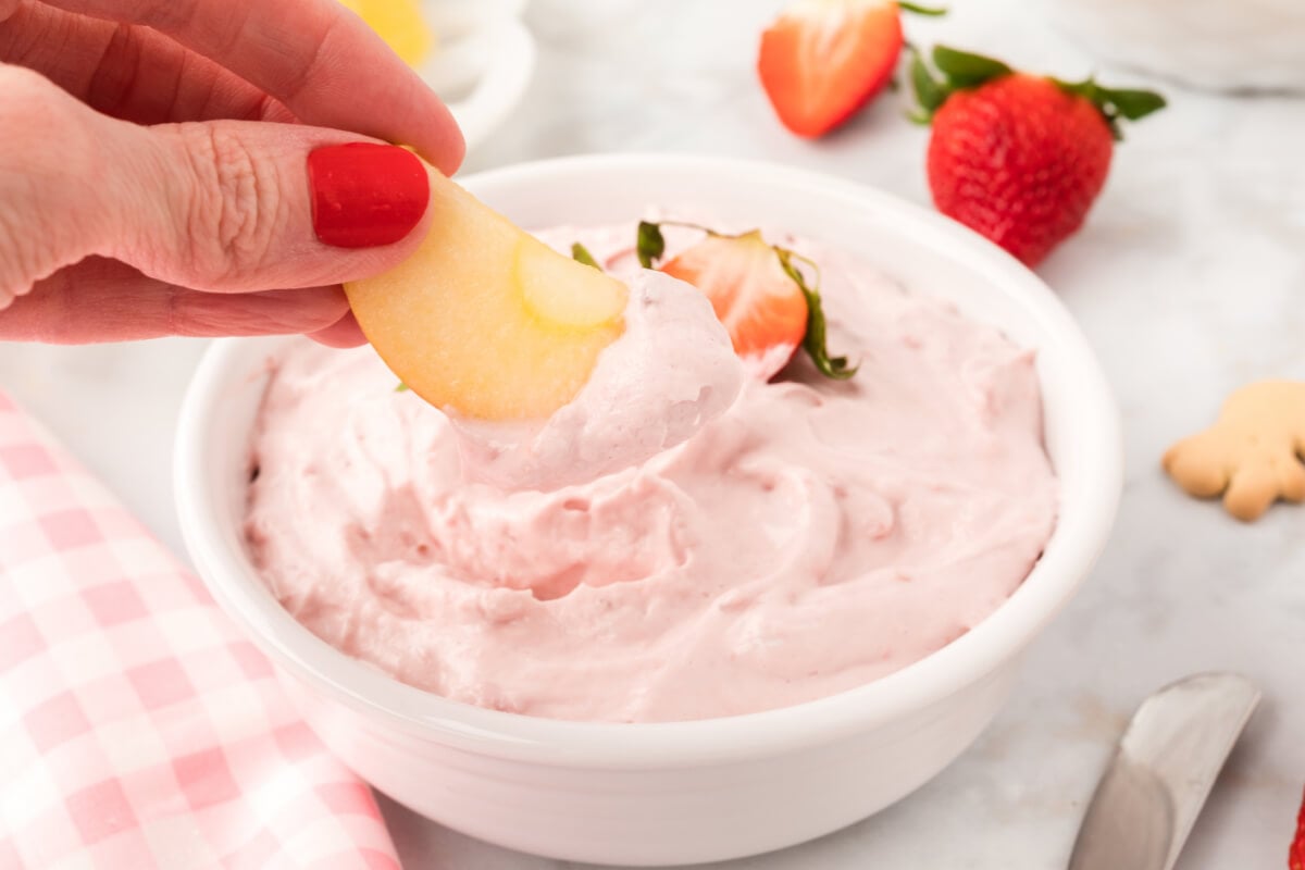 apple slice being dipped into strawberry dip