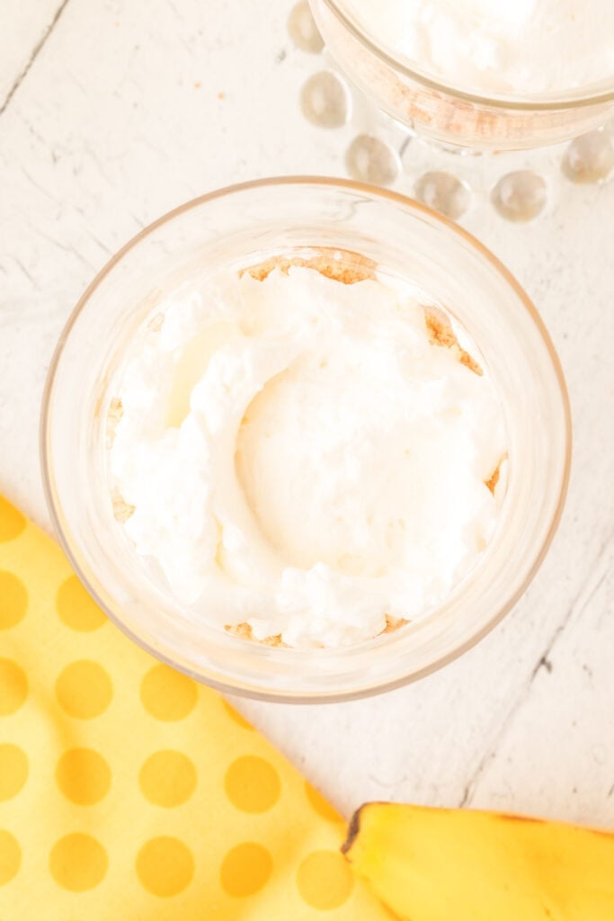 whipped cream layered on top of banana pudding in a parfait glass