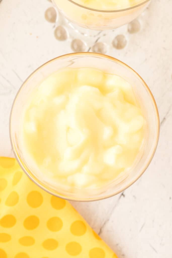 banana pudding poured over sliced bananas in a dessert glass