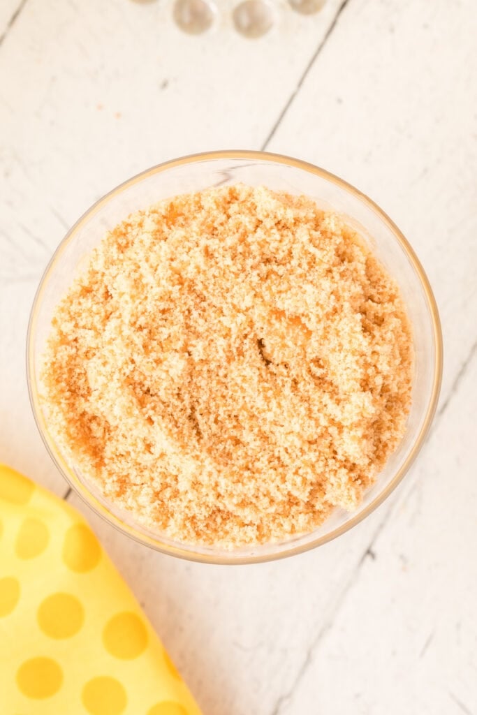 layer of crushed cookies added on top of banana pudding in a glass cup