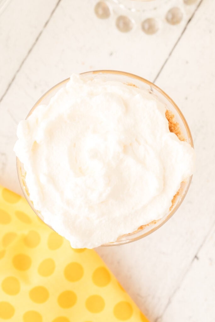 whipped cream spread over cookie layer in banana pudding parfait
