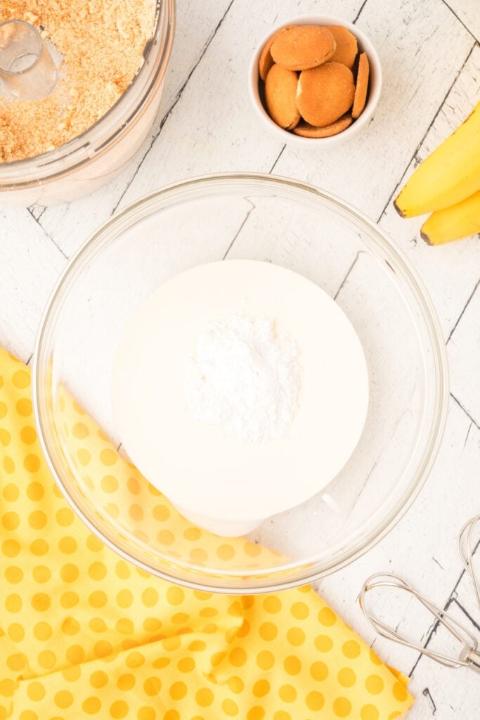 cream and powdered sugar in a glass bowl before whipping cream for banana pudding parfait
