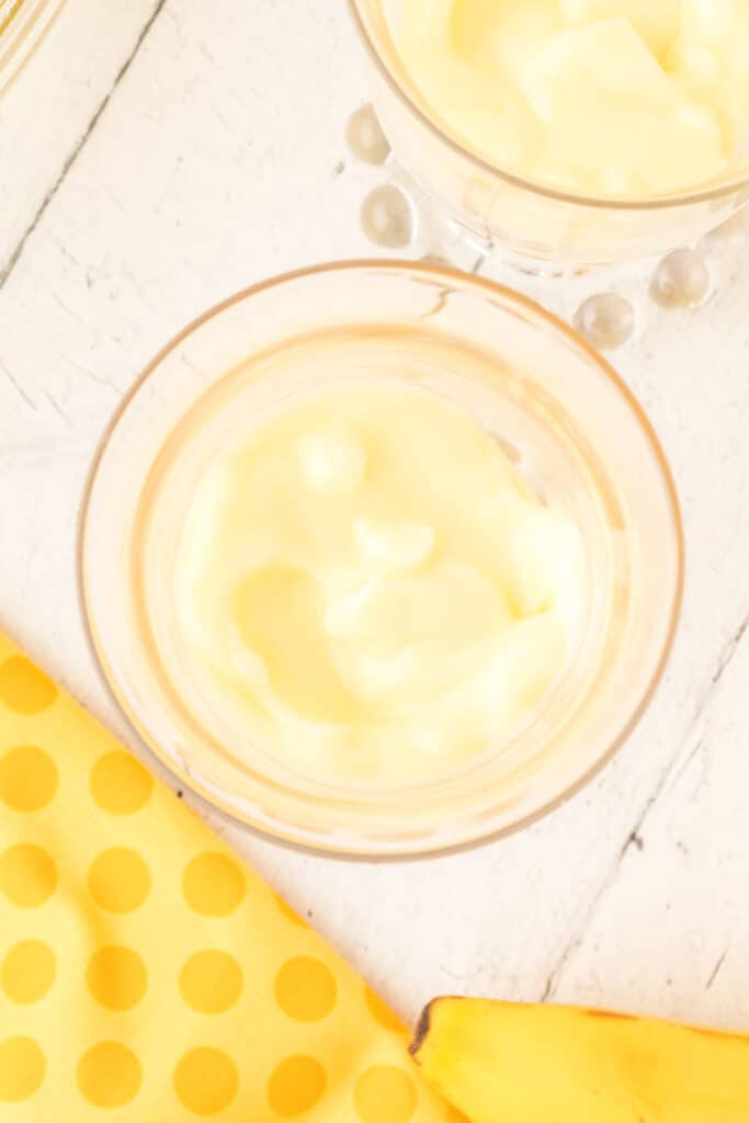 banana pudding mixture spooned over cookie crumbs in a dessert glass
