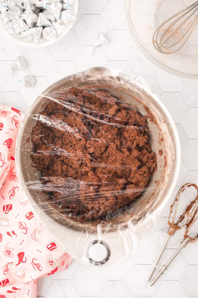 Chocolate Blossoms cookie dough covered with plastic wrap and chilling in a mixing bowl