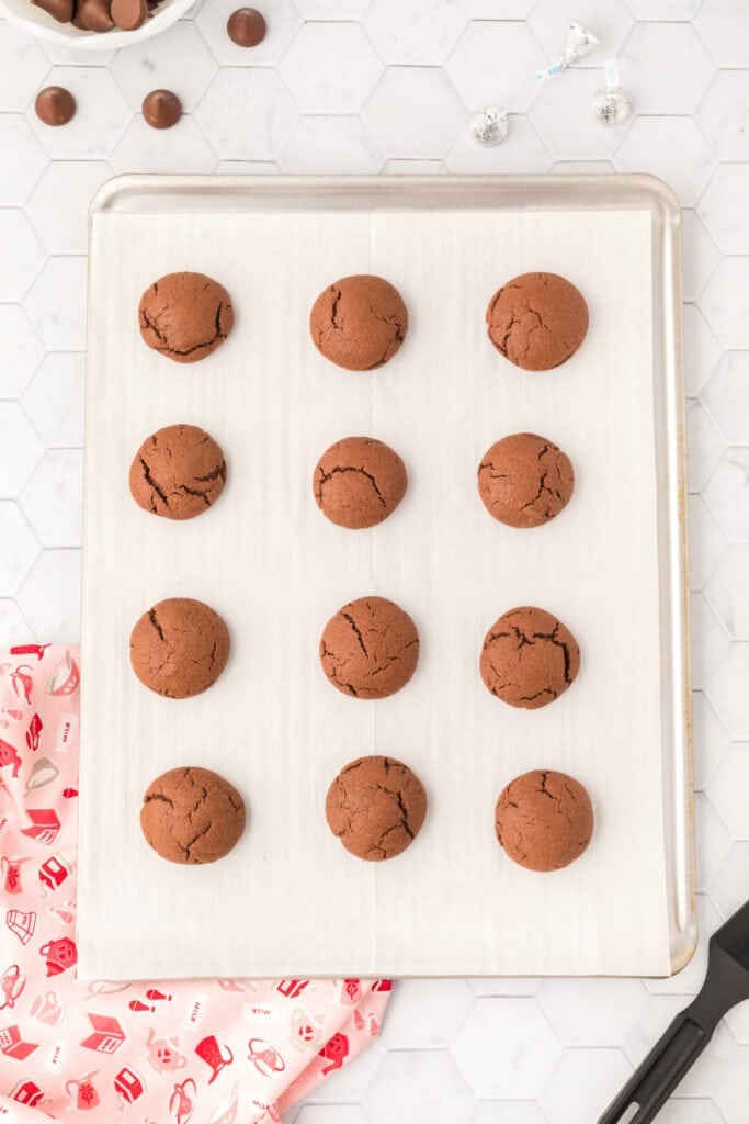 Baked Chocolate Blossoms cookies on a parchment-lined baking sheet before adding Hershey's Kisses